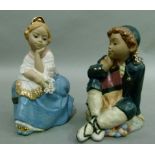 A pair of Nadal pottery figures of young male and female figures, she holding a bunch of flowers, he