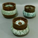 Three brown glazed pottery tobacco jars, each with a band of green marbling, 13cm and 11cm high