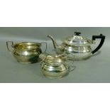 An Edward VIII silver three piece tea service in George III style, ebonised fitting and angular