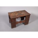 An African stool or table, the rectangular top relief carved with a central figure holding staffs,