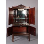 An Edwardian mahogany drinks cabinet with ornate foliate carved serpentine top, the frieze carved