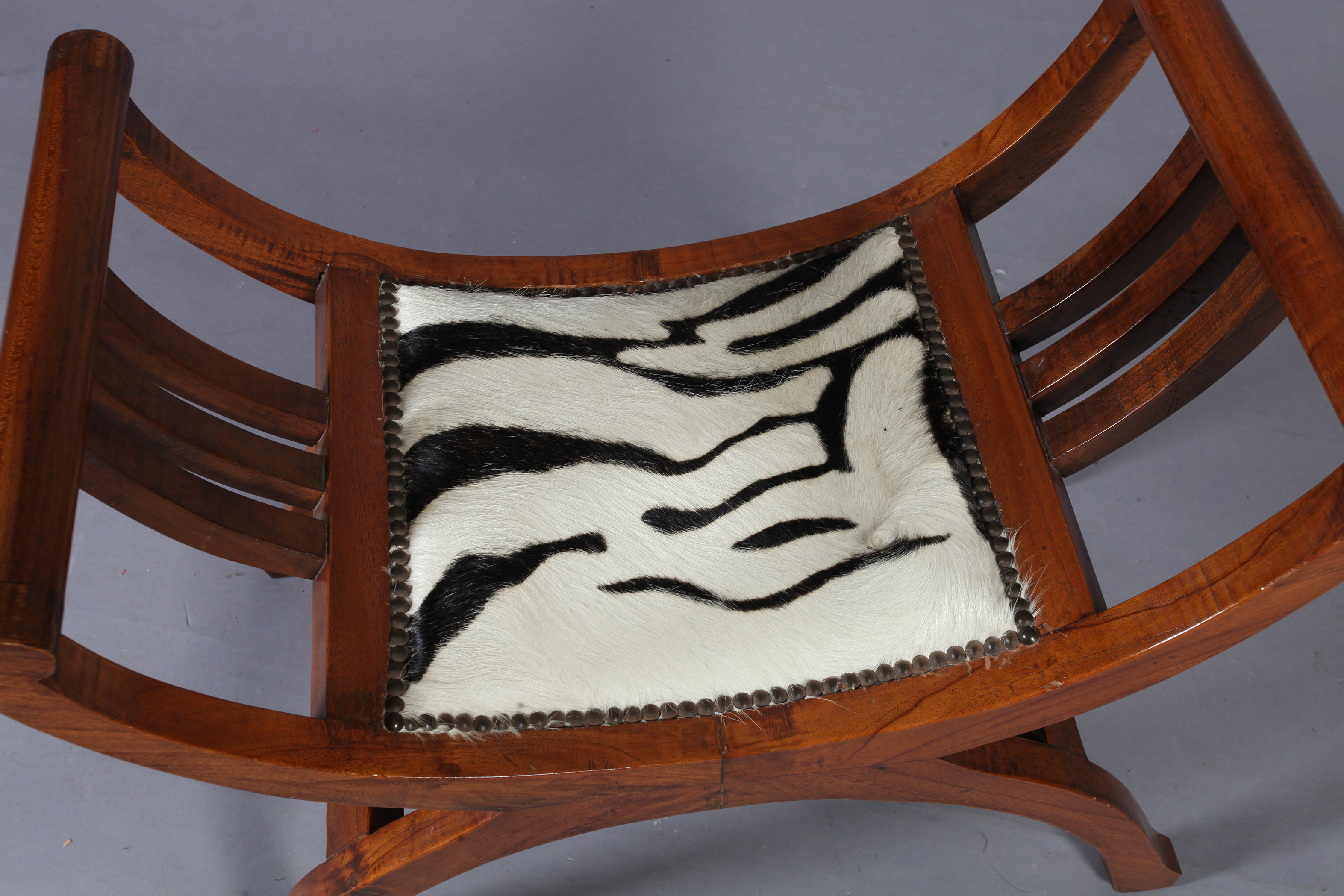 A reproduction hardwood x-frame stool, the seat upholstered with zebra skin within close brass - Image 3 of 4