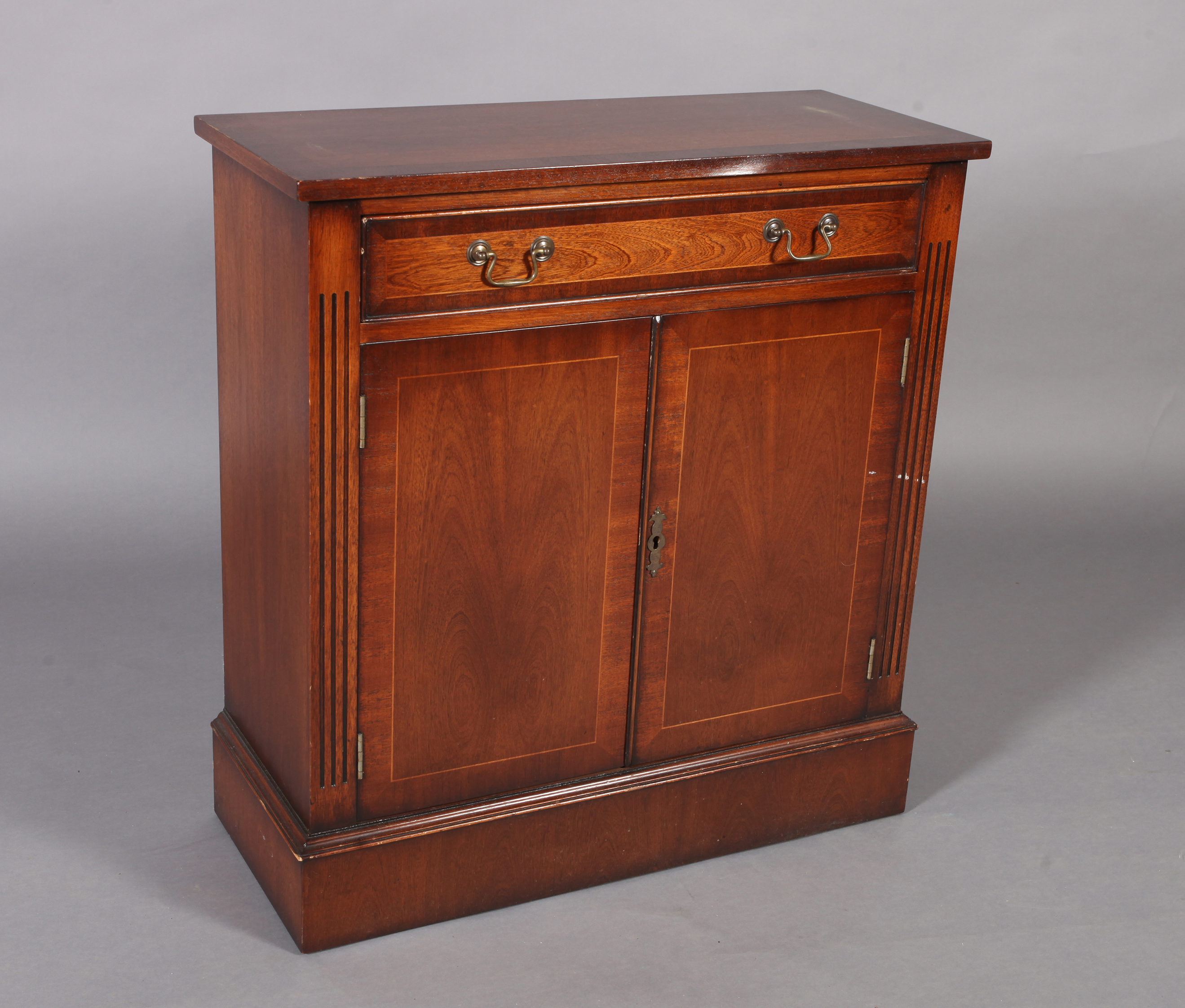 A reproduction mahogany cupboard crossbanded and box wood strung, the single frieze drawer baize