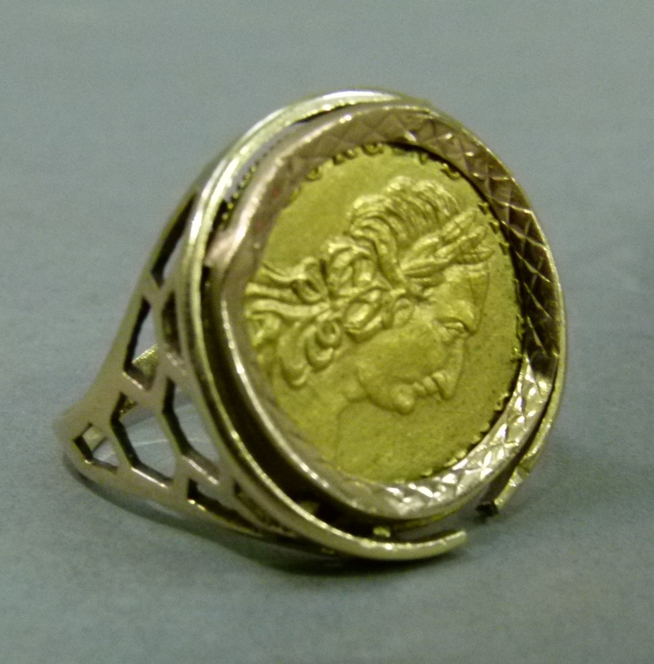 A coin ring mount in 9k gold at fault holding a base metal token