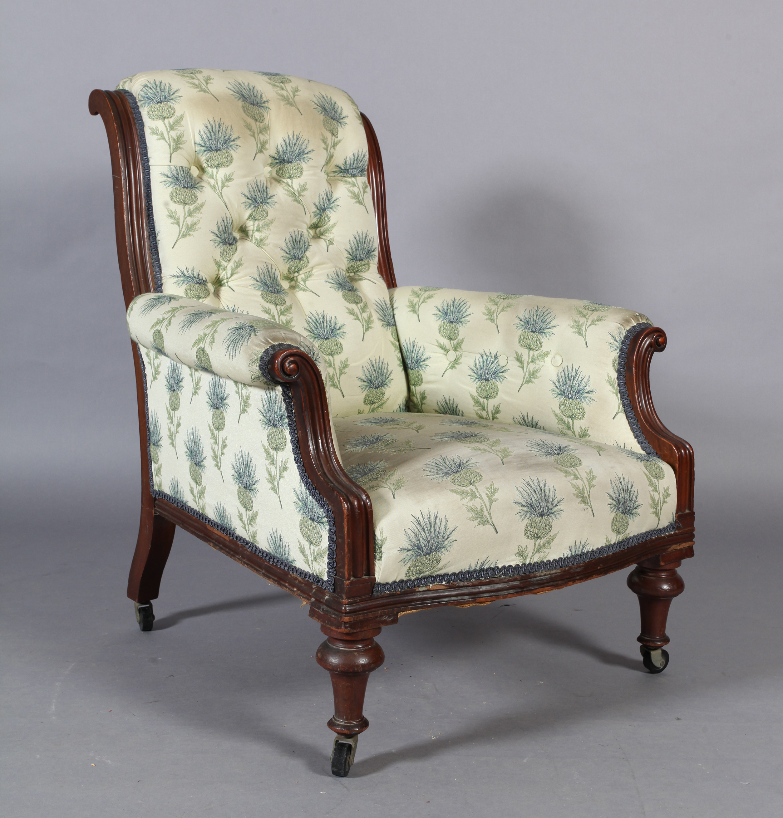 A Victorian mahogany framed elbow chair with upholstered scroll over back and arms, the bowed feet