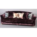 A large three seater sofa upholstered in purple velvet, on short square tapered legs