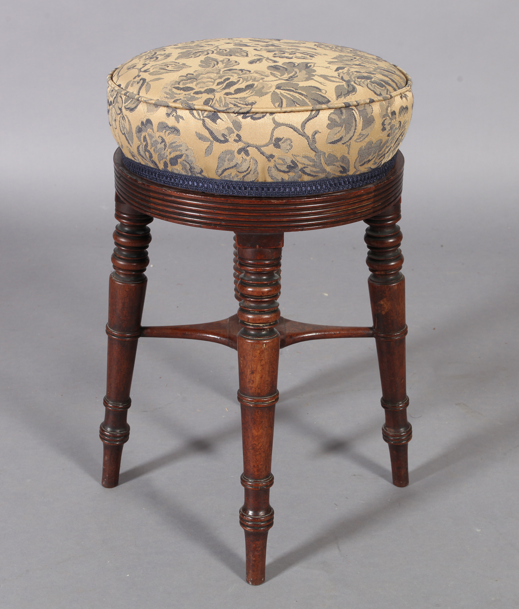 A post Regency mahogany revolving circular music stool, the stuffed over top with reeded rim, four