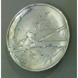 A Japanese silver coloured metal small circular dish, cast to the front with finches amidst