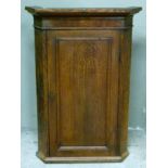 A George III oak hanging corner cupboard with flared cornice and mahogany veneered frieze,