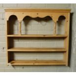 A pine dresser rack with arched and serpentine shaped frieze, pair of baluster pillars, three