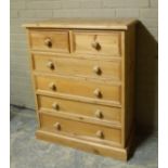 A reproduction pine chest of drawers fitted with two short and four long panelled drawers, skirted