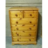 A reproduction pine chest of two short over four long graduated raised fielded panelled drawers,