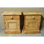 A pair of pine bedside cupboards, the tops above one drawer and panelled cupboard on skirted