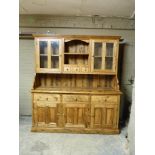 A reproduction pine dresser with flared cornice, the back with central shelf, three small drawers