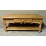 A pine two tier coffee table, the rounded rectangular top above a shaped frieze fitted with one