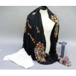 A black shawl embroidered with flowers in multi-colours, tasselled fringe, together with two