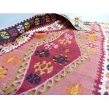 A Kilim, the pink ground woven in green, red, orange and black with three diamond motifs to the