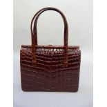 A Chestnut brown crocodile skin handbag with twin loop handles and gilt metal strap, 26cm wide