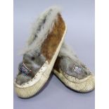 A pair of fur and hide moccasins, each with beadwork panel