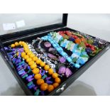 A jewellery box with a glazed lid containing approximately fourteen bead necklaces by maker's