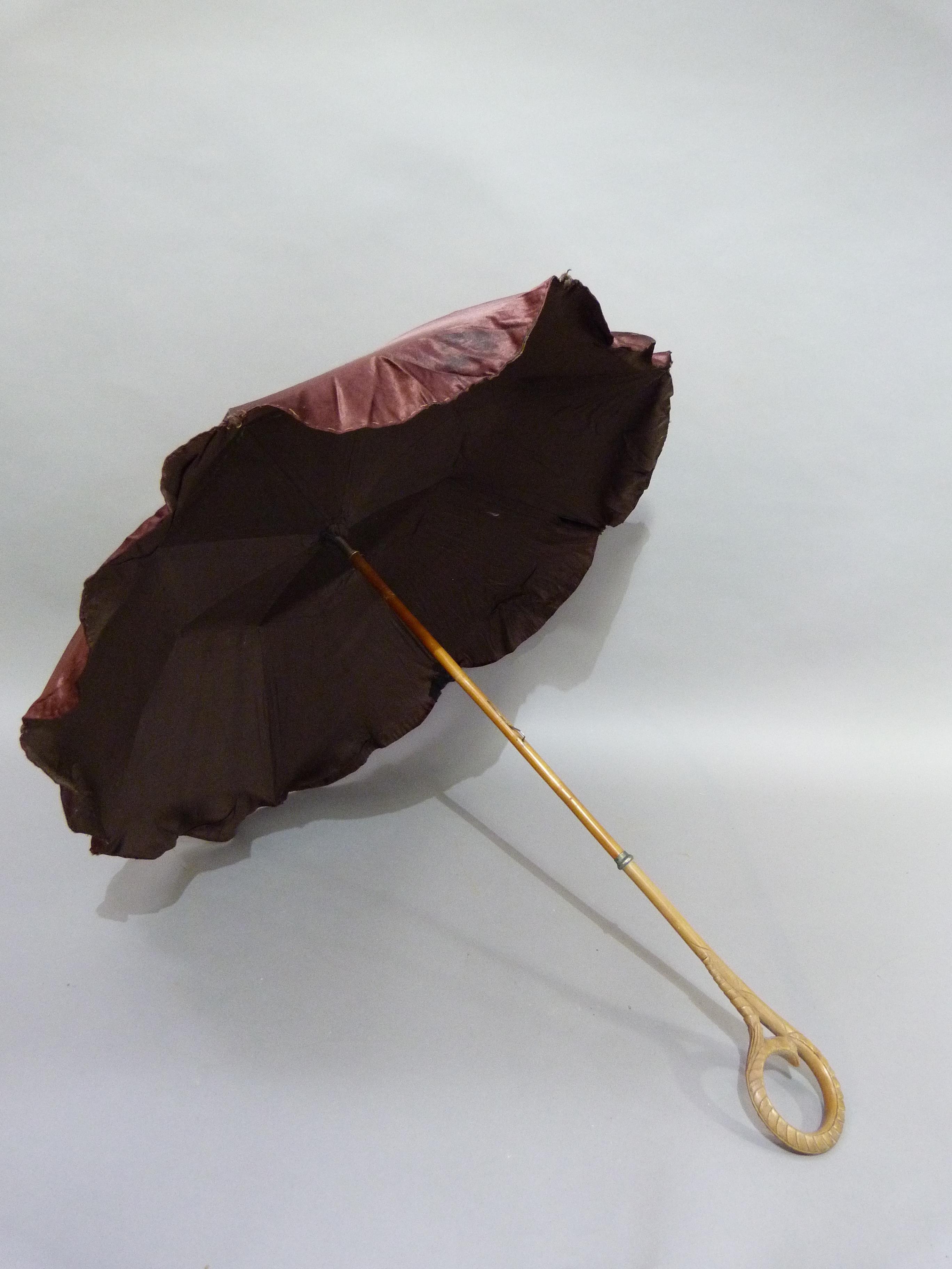 A Late Victorian aubergine satin parasol, the handle finely carved in a loop