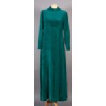 Marjorie Robb, an emerald green velvet full length evening gown with stand up collar, button