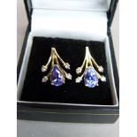 A pair of tanzanite and diamond earrings, each claw set with a pear shaped facetted tanzanite and