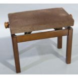 A modern adjustable piano stool with upholstered seat on square legs