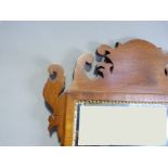 A reproduction mahogany fretted frame wall mirror in George III style with shaped cresting base