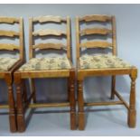 A set of four reproduction oak ladder back dining chairs with drop in seats on turned legs joined by