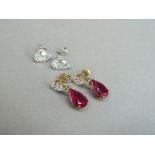 A pair of ear pendants, each claw set with a pear shaped facetted ruby pendant from a pear shaped