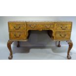 A reproduction burr walnut veneered inverted breakfront desk, the top inset three red leather