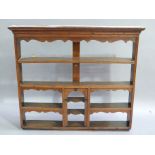 A George III oak dresser rack with flared cornice, shaped canopy, shelved back, centred at the