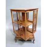 An Edwardian mahogany revolving bookcase the serpentine shaped square top above spindle galleries on