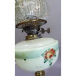 A late nineteenth century brass oil lamp having an opaque glass reservoir painted with flowers, a