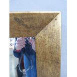 A modern wall mirror with deep patinated gold painted frame and bevelled plate, 113cm wide, 89cm