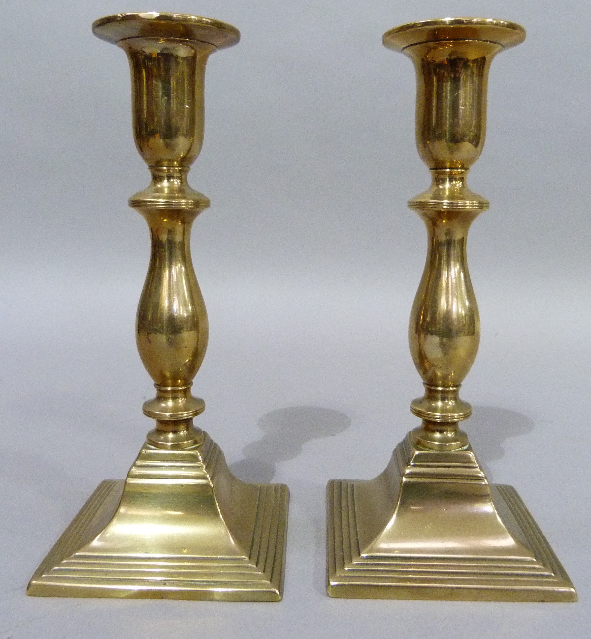 A pair of nineteenth century brass candlesticks of baluster outline on square stepped bases, 19cm