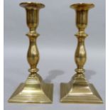 A pair of nineteenth century brass candlesticks of baluster outline on square stepped bases, 19cm