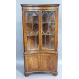 A reproduction mahogany standing corner cupboard in George III style, the dentil moulded cornice