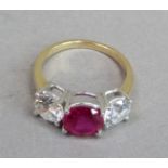 A three stone ring, the circular facetted synthetic ruby flanked by two cubic zirconia in yellow