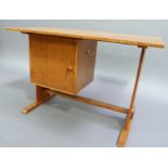 An oak arts and crafts child's desk, the rectangular top above cupboard inset to left side,