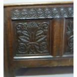 A late 17th century oak blanket chest the plank top above a three panel front carved fruit and