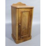 A late Victorian walnut pot cupboard having a short arched back above a single indented panel door