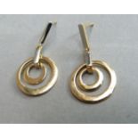 A pair of ear pendants, each hung with concentric pierced hoops from two letter links, on post and