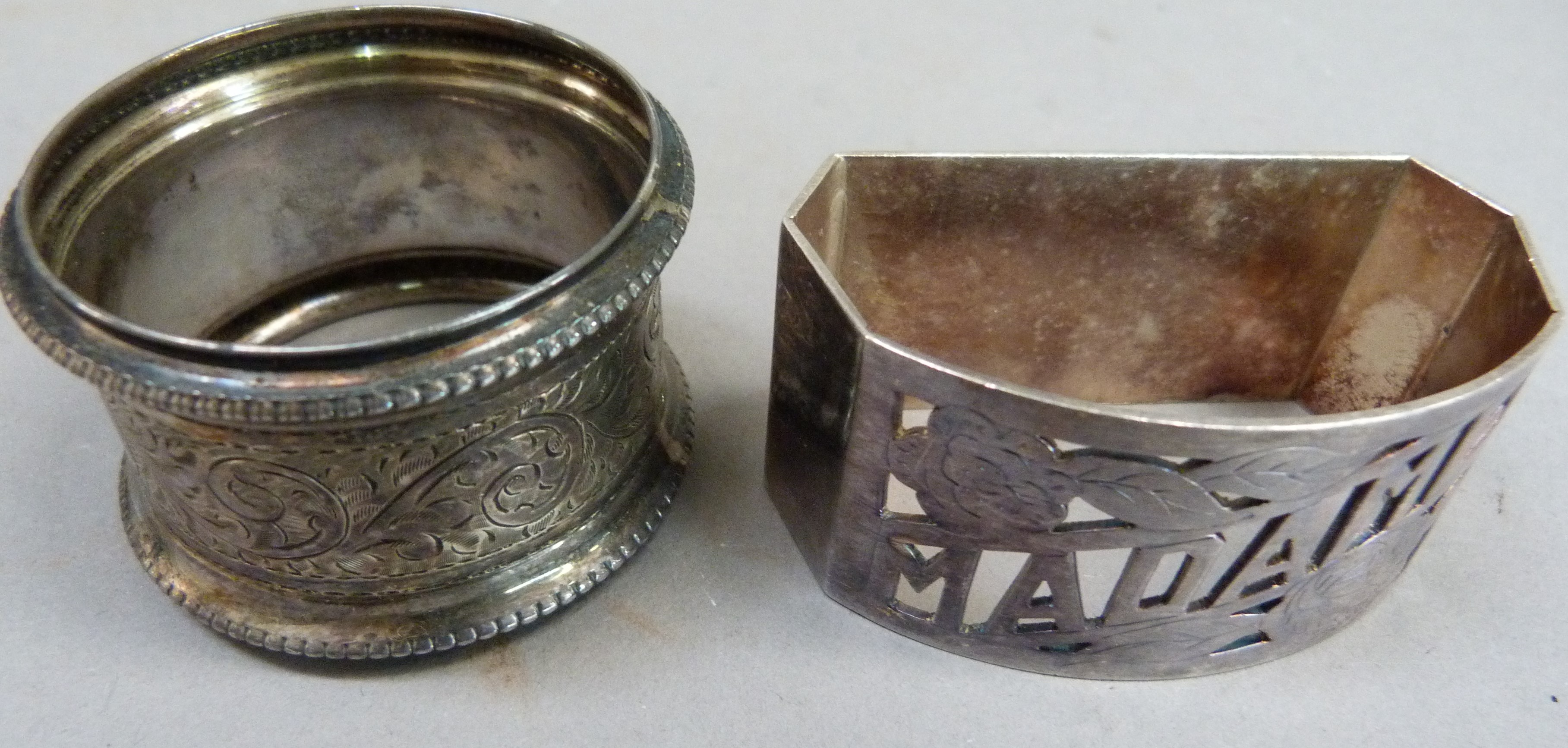 A silver napkin ring engraved with foliate leaf curls, with initial together with a white metal - Image 2 of 4