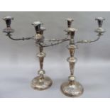 A pair of silver plated, three light candelabra having reeded twin arms with foliate decoration, the