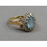 A blue topaz and diamond cluster ring in 18ct yellow and white gold, claw set to the centre with