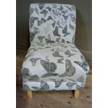 A modern occasional chair upholstered in butterfly fabric on short beech legs