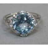 An aquamarine ring in silver, claw set to the centre with the circular facetted stone with further