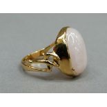 A rose quartz dress ring in silver gilt, the oval cabochon stone collet set, flanked by pierced